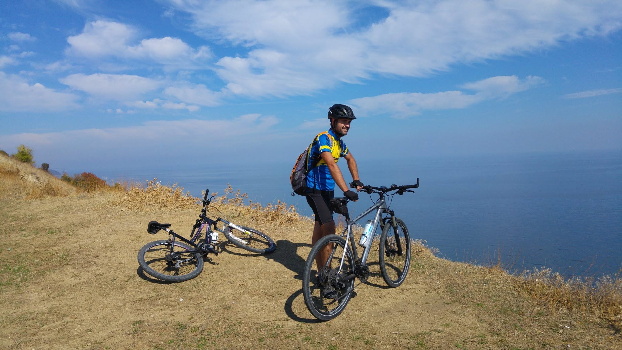 Vladimir Paskov smiling beside two mountain bikes while looking over the Black Sea near Cape Emine